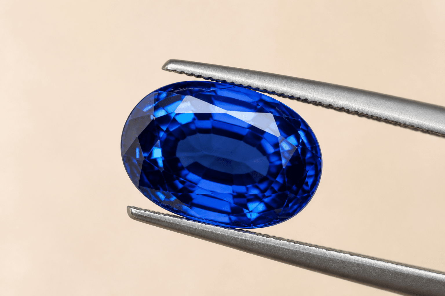 Brilliant royal-blue oval sapphire after restoration, held in tweezers