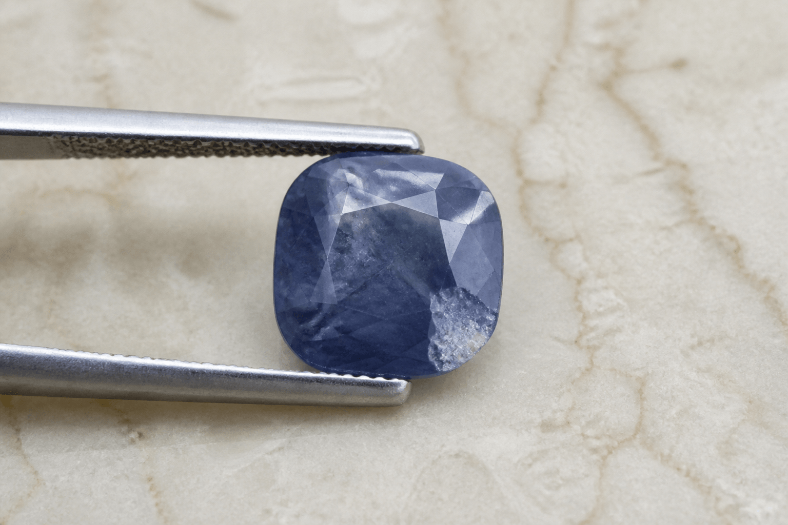 Cushion-cut blue sapphire with a visible chip on the girdle before repair